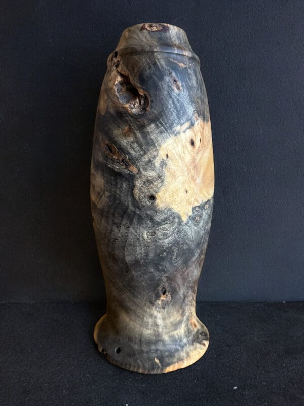 A tall vase with some brown and black spots on it